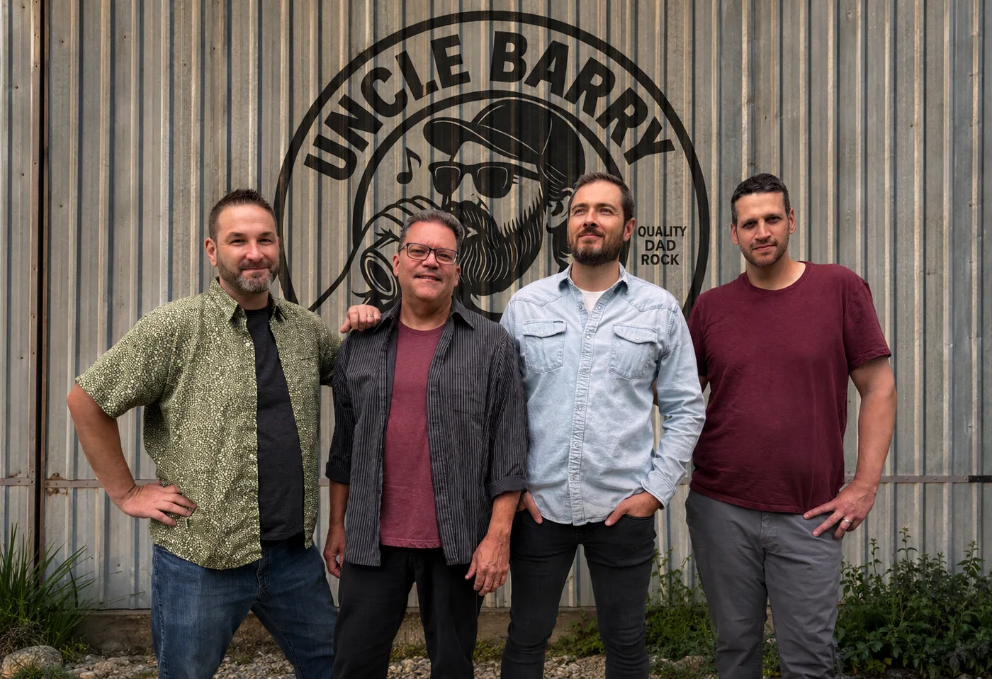 Uncle Barry — Josh Reiter, Nick Eberts, Richard Voigt and Greg Faucher in front of the band's logo painted on a corrugated metal wall
